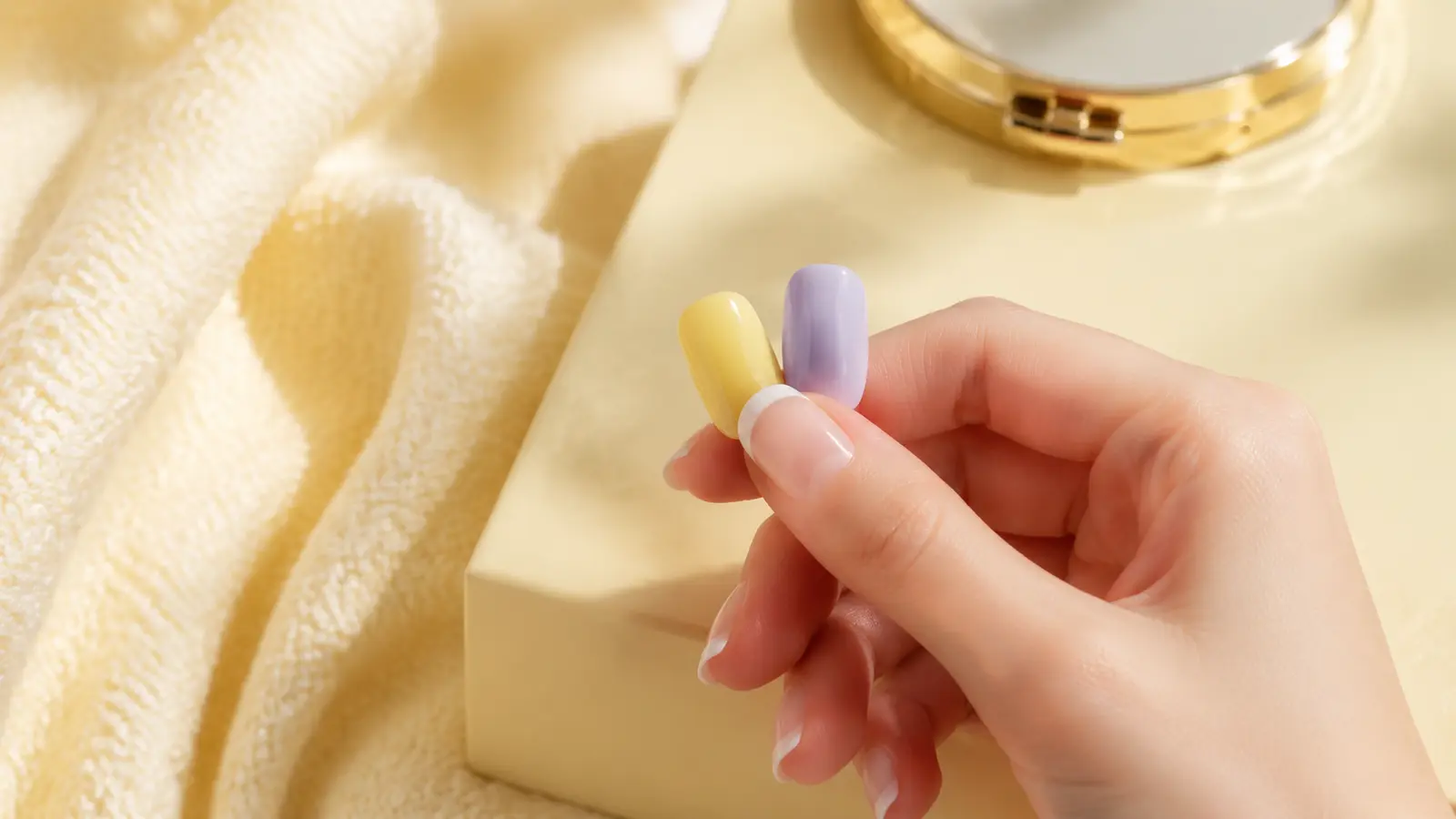 Comparing butter-yellow and lavender press-on candidates while choosing a width that covers the broadest part of a natural thumbnail.